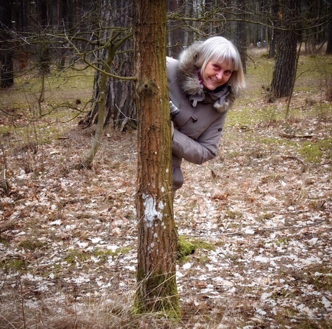 Ljushårig kvinna kikar fram bakom ett träd.